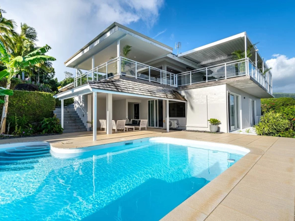 Propriété moderne avec piscine et vue sur la mer à Toahotu, Tahiti, entourée de végétation tropicale.