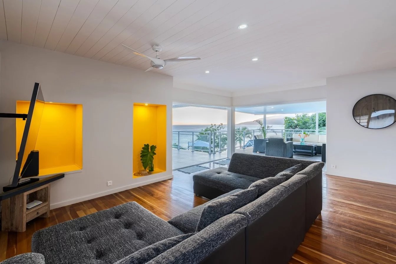 Intérieur d’une propriété à Toahotu, Tahiti Intérieur d'une propriété moderne avec salon, télévision et accès à une terrasse extérieure.