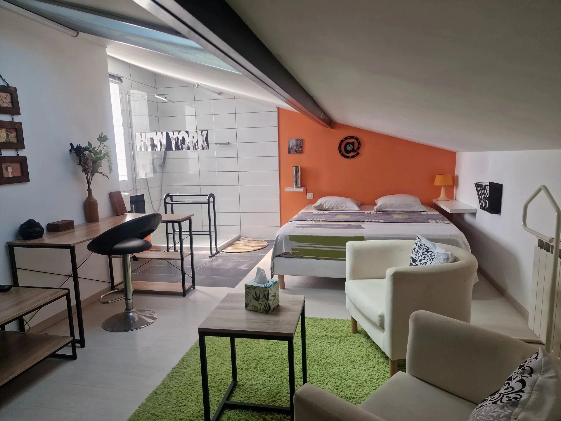 Chambre moderne à la Villa Marine de Solaro Chambre moderne avec lit double, coin salon et salle de bain ouverte, décorée avec des touches de couleur.