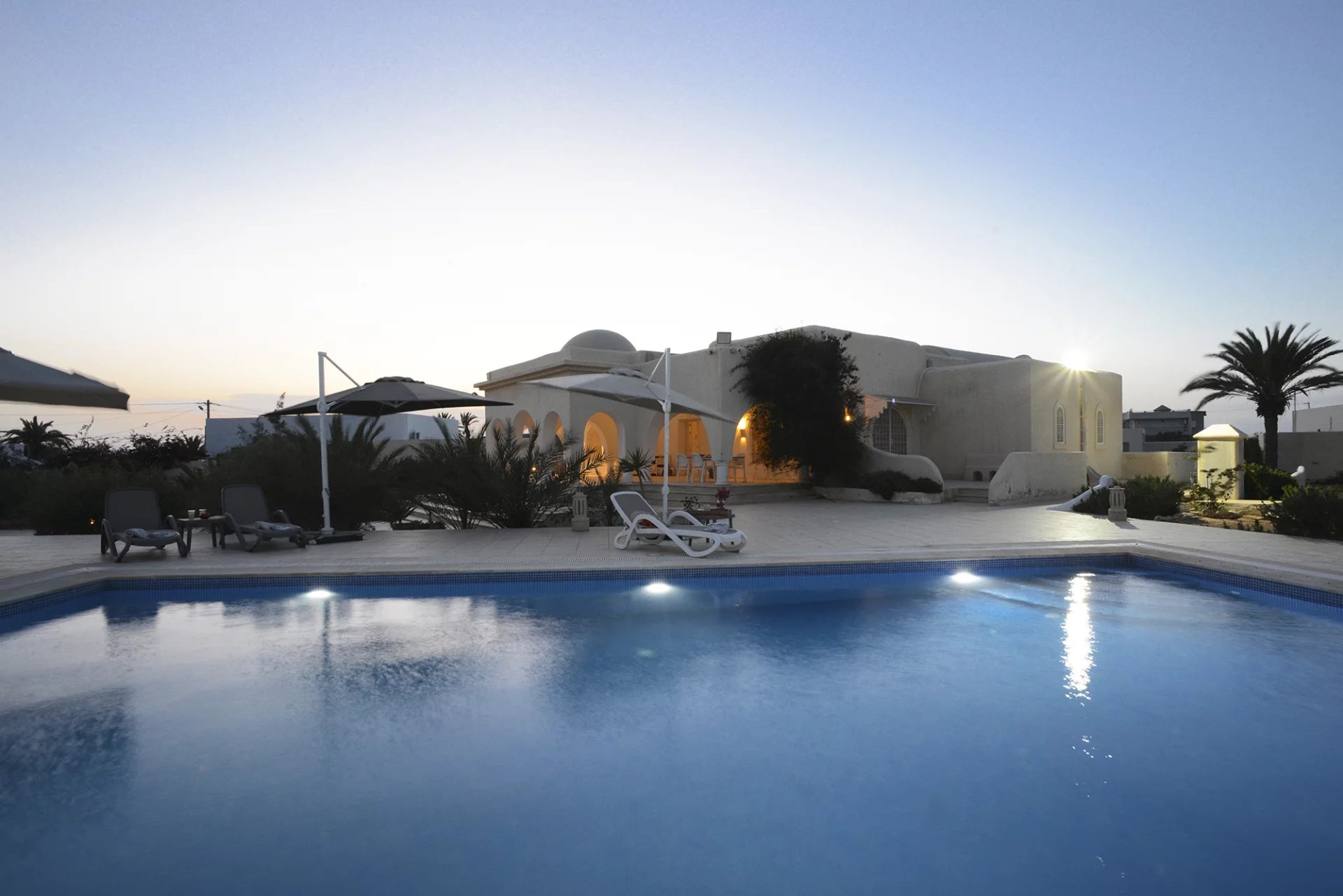 Villa blanche et piscine à la tombée du jour dans le domaine de Kerkennah