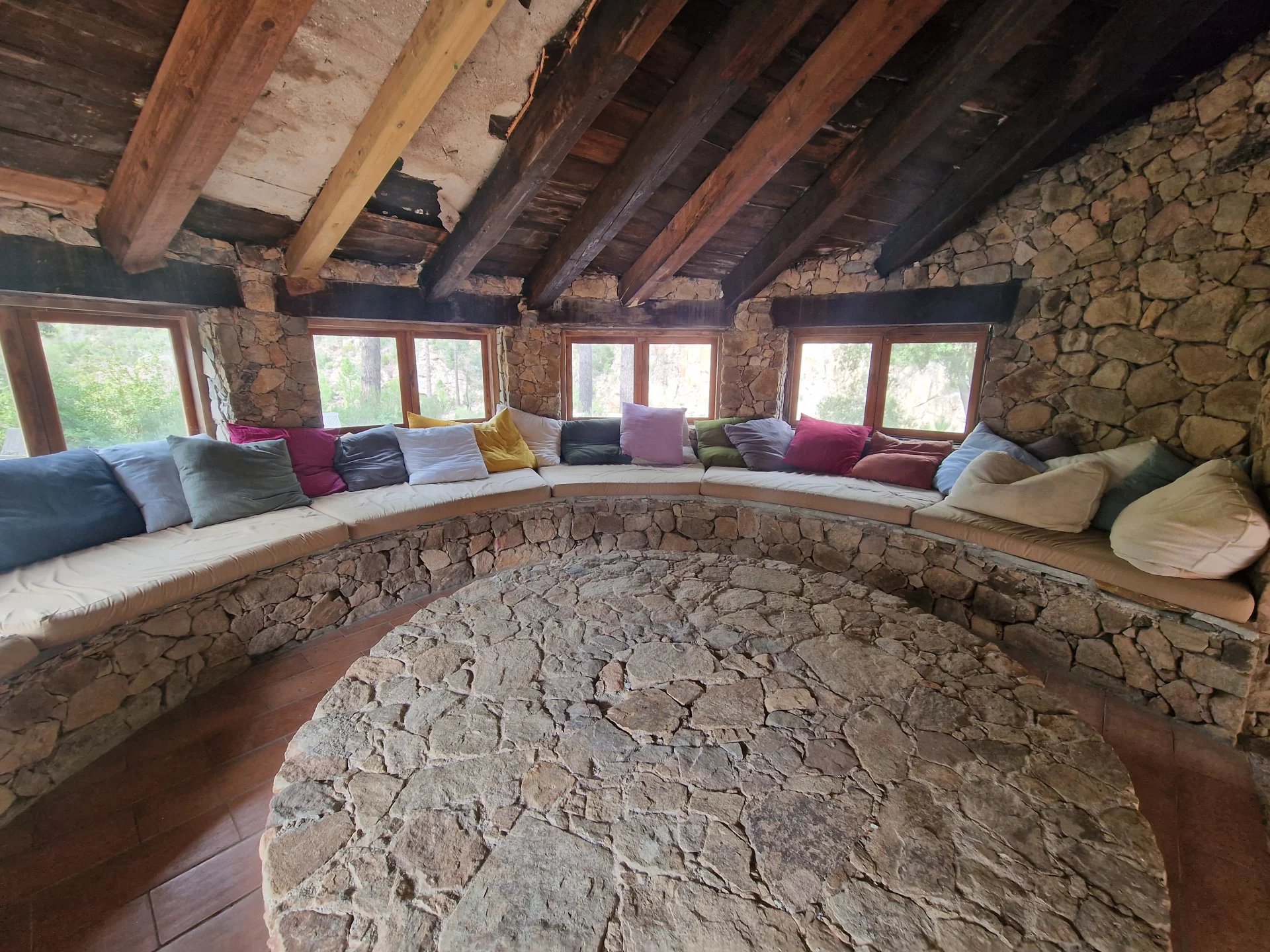 Intérieur d’une bastide en pierre à Sari-Solenzara Intérieur d'une bastide en pierre avec un coin salon circulaire et des coussins colorés.