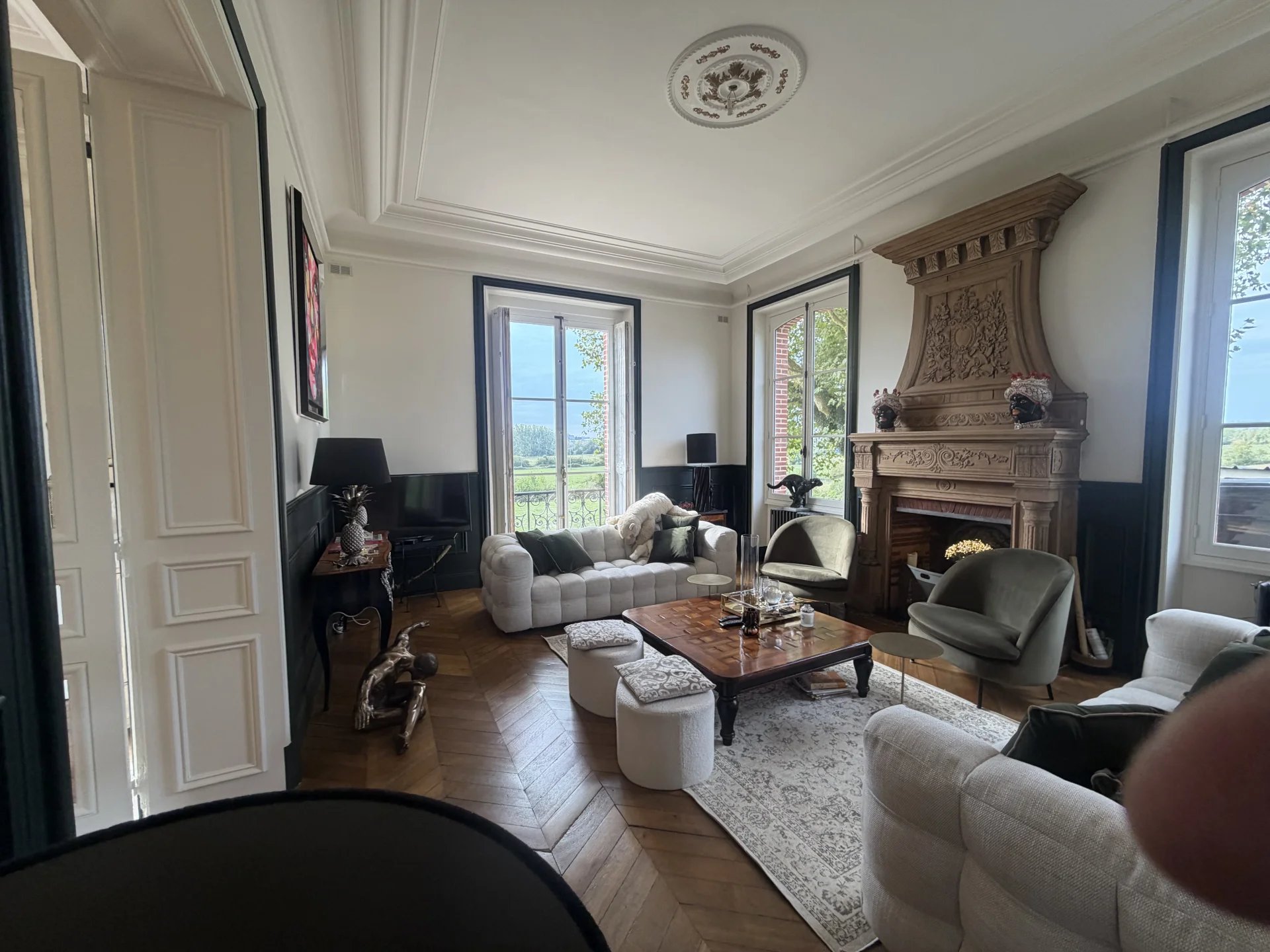 Intérieur d’un château près de Pont-l’Évêque Intérieur d'un château avec salon élégant, cheminée et grandes fenêtres sur un domaine près de Pont-l'Évêque.