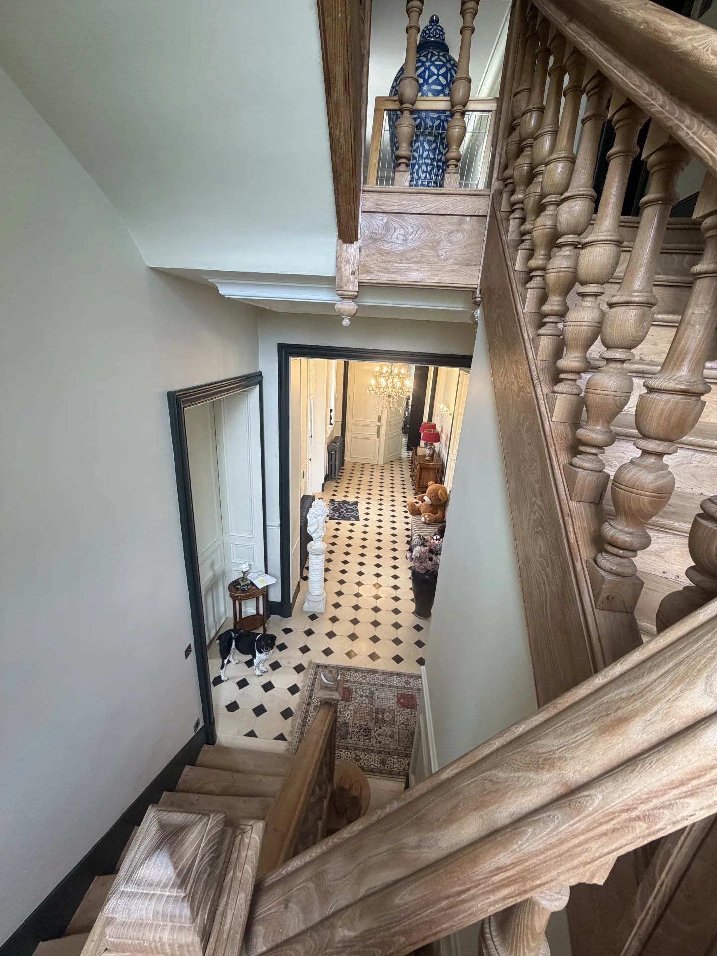 Intérieur du château équestre Escalier en bois menant à un hall d'entrée avec carrelage noir et blanc dans un château