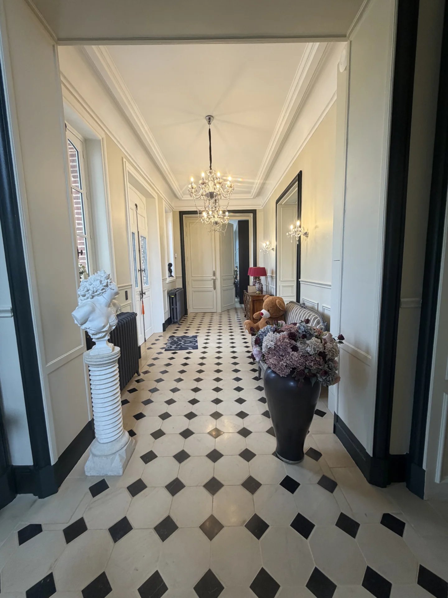 Intérieur d’un château près de Deauville Intérieur d'un château avec un couloir décoré de carrelage en damier et des éléments de décoration élégants.
