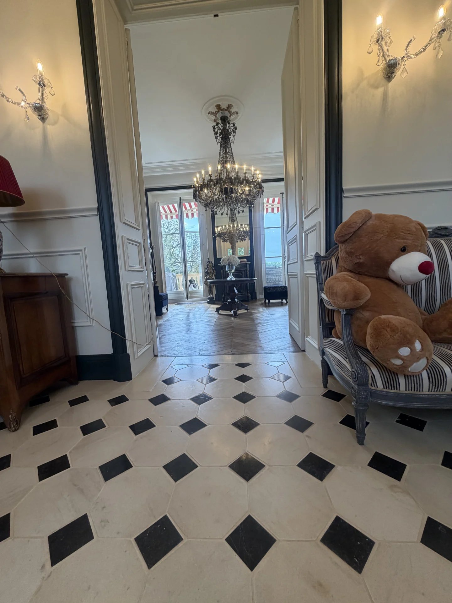 Intérieur du château équestre Intérieur d'un château avec un sol en carreaux, un lustre et un ours en peluche sur une chaise.