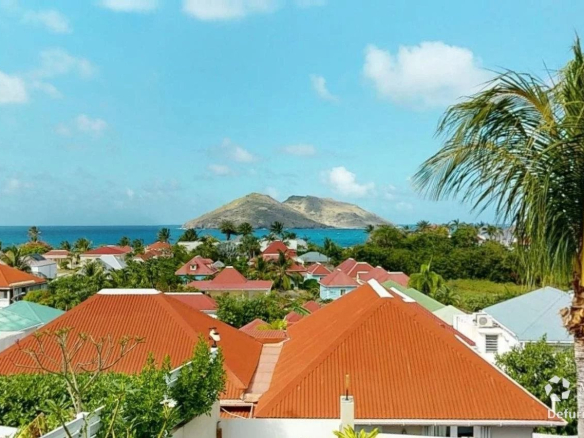 A tropical coastal neighborhood with orange tiled roofs and palm trees overlooking the sea and distant islands Propriétés clovis