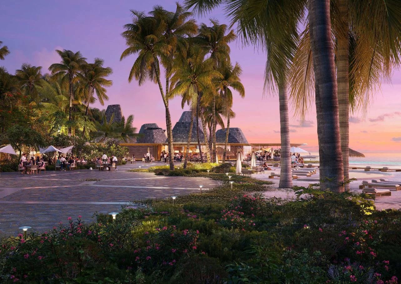 Tropical resort terrace at sunset with palm trees, outdoor dining, and beach loungers nearby.