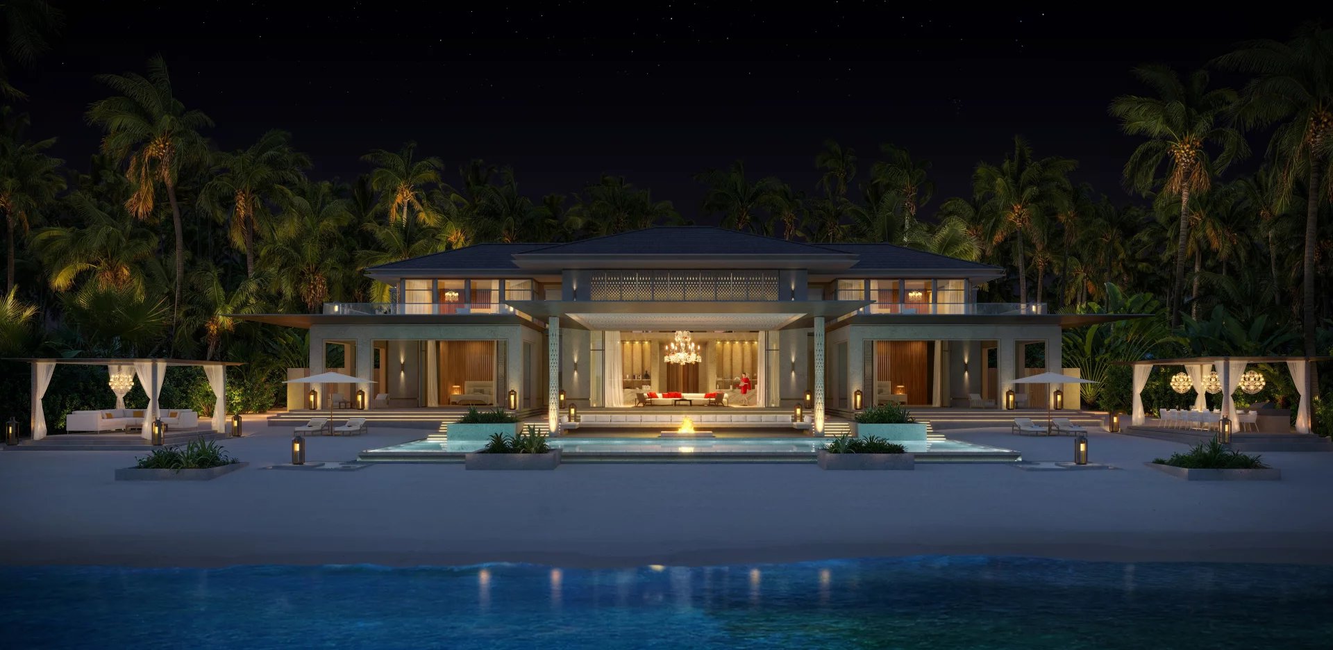 Luxurious beachfront villa at night with a glowing courtyard pool and palm trees surrounding the property Propriétés clovis