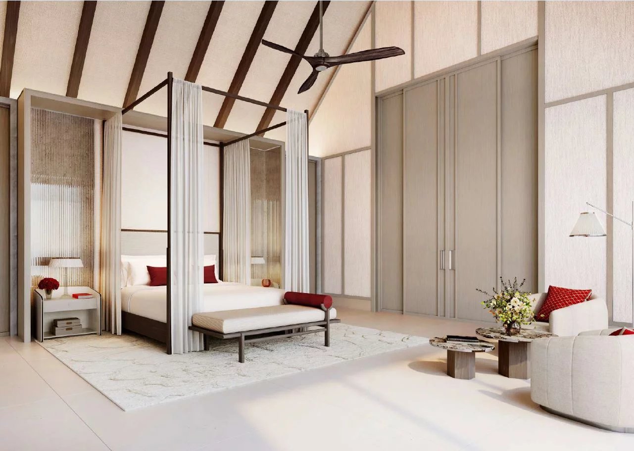 Luxurious bedroom with a four‑poster canopy bed, sheer curtains, and a matching seating area in a bright suite.