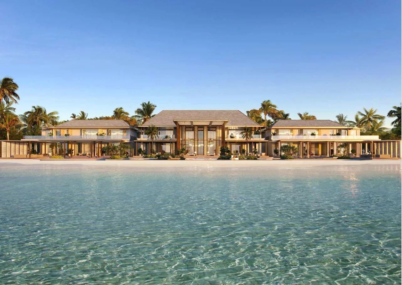 Luxurious two-story waterfront villa with glass foyer, palm-lined grounds, and clear blue water