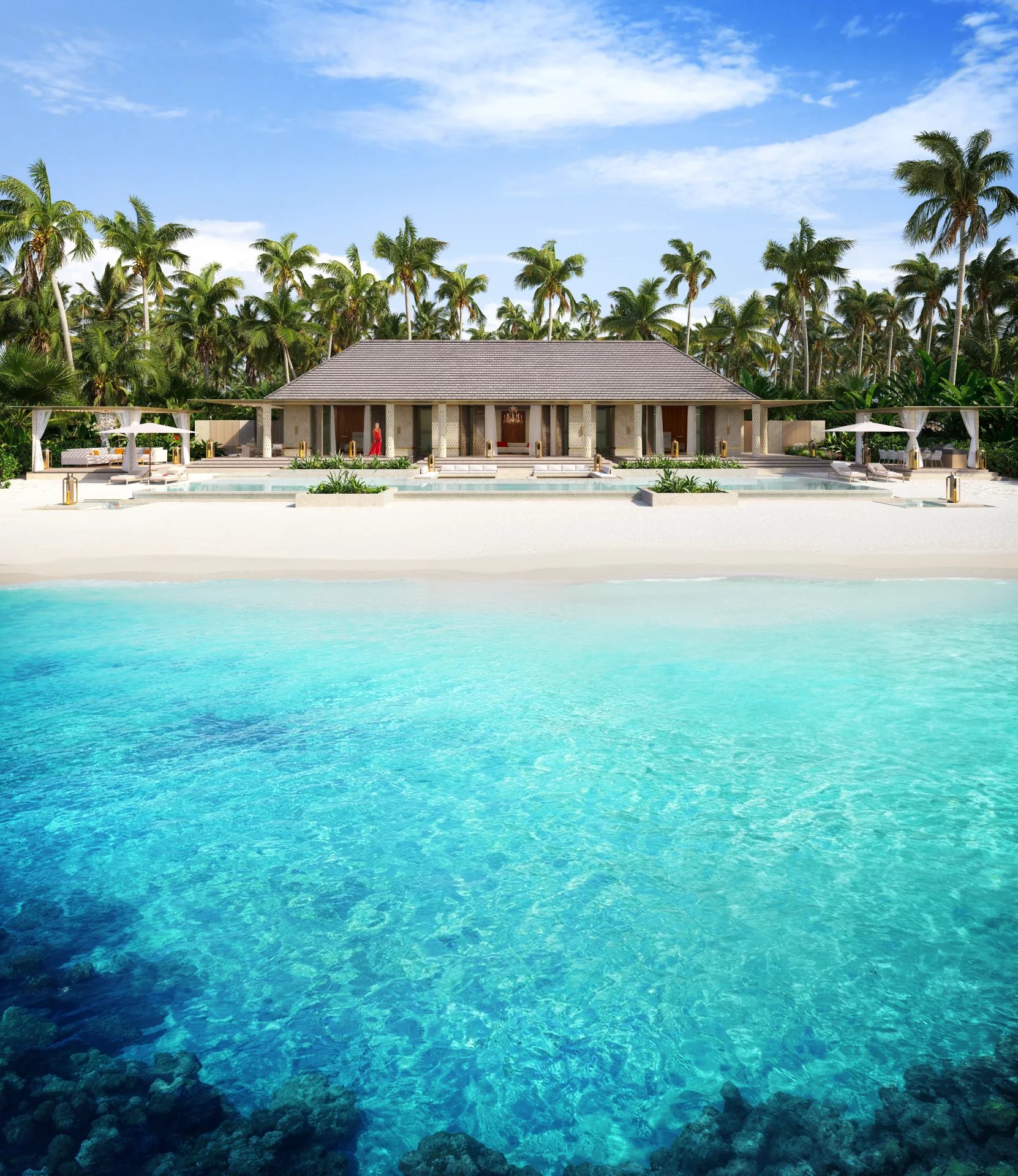 Luxurious beachfront villa with a thatched roof, white sand, and turquoise sea surrounded by palm trees ahead of a resort pool area.
