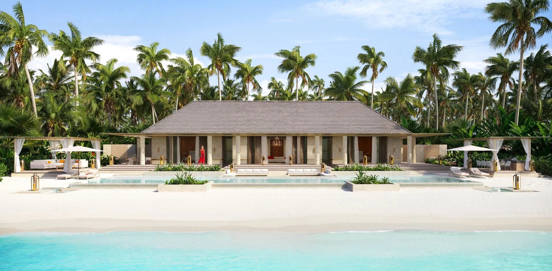 Luxury beachfront villa with a tiled roof, palm trees, and a clear blue sky over a resort pool area.