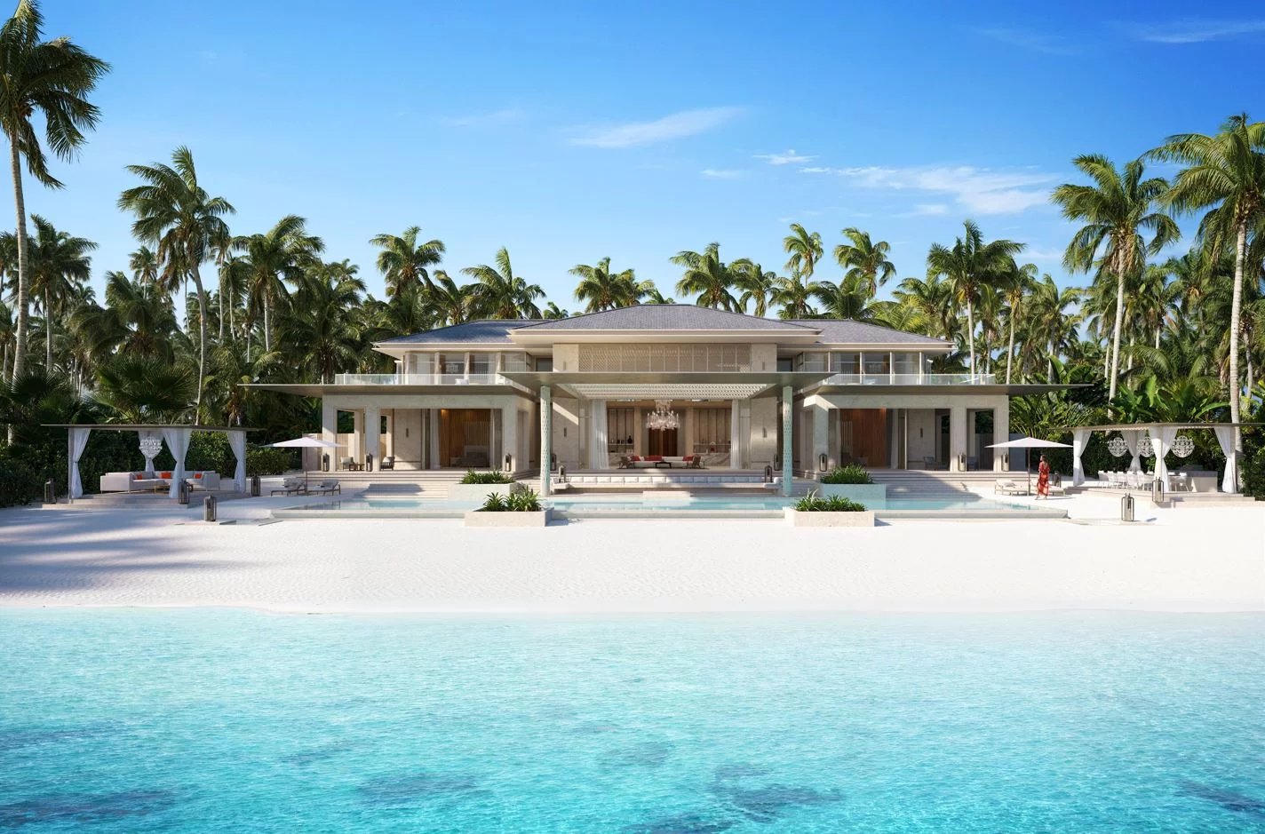 Luxurious beachfront villa with a modern two-story design, open terraces, and palm-fringed surroundings on a white sandy beach.