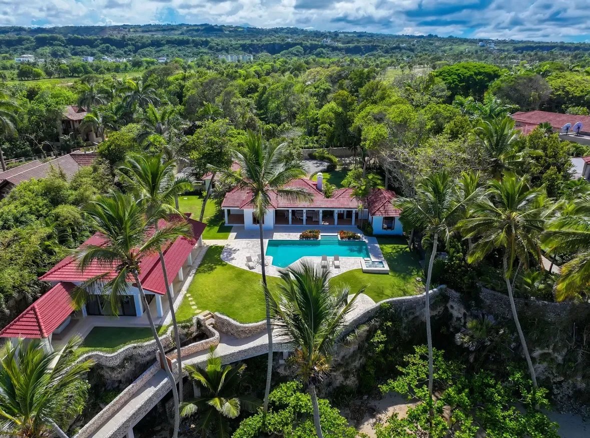 Aerial view of a tropical resort with red roof villas a rectangular pool and palm lined green lawns Propriétés clovis