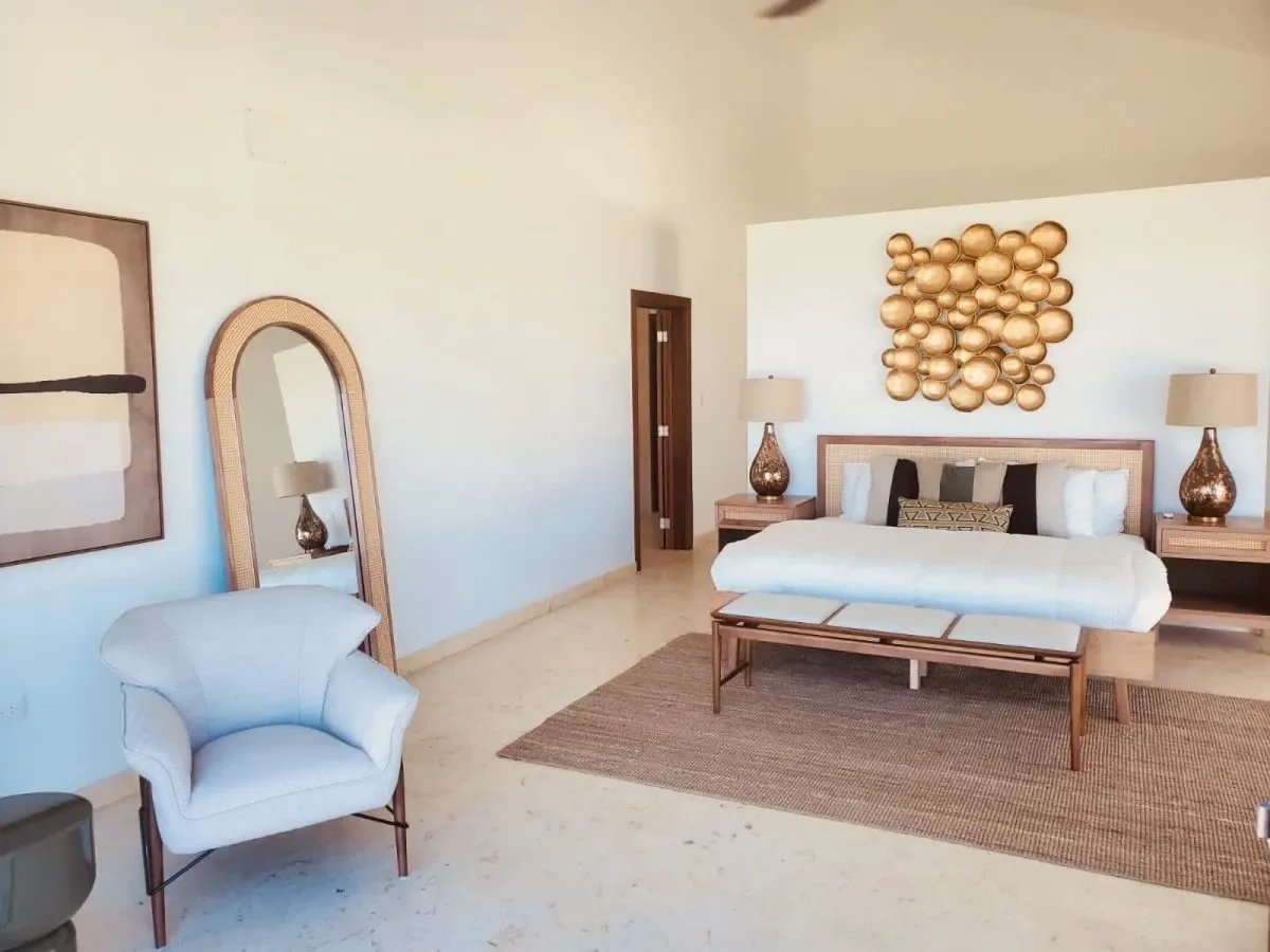 Bright, modern bedroom with a white bed, beige textiles, and two matching lamps on wooden nightstands.