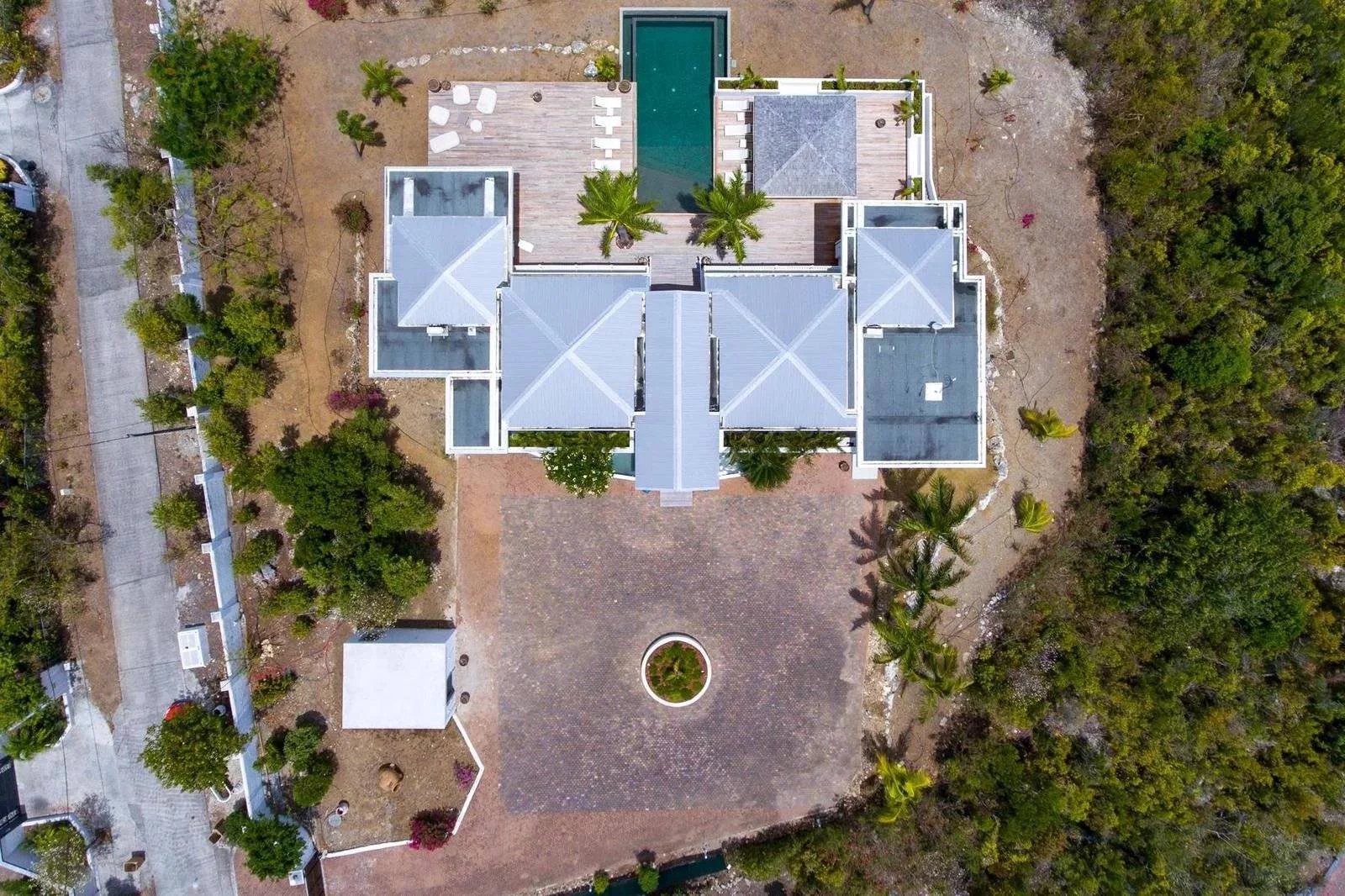 aa7e91dfd90aef3037b8453be1b0a93a_aebcde7261_1600-original Aerial view of a large modern villa with a central courtyard and palm-lined perimeter, surrounded by trees and dry landscaping.
